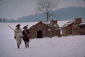 Soldiers at a snow-covered winter camp, with crude log huts behind them