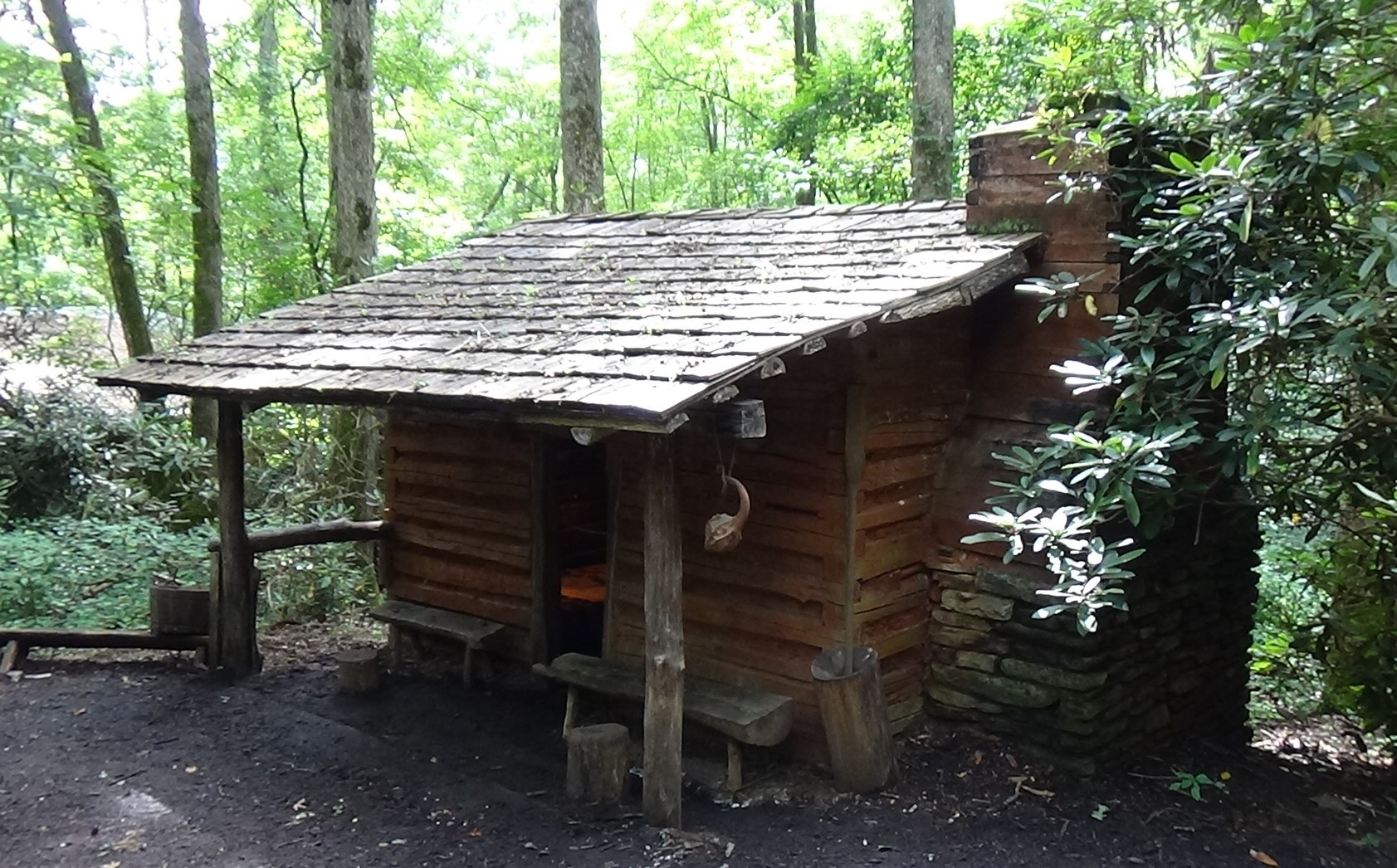 Single-story log cabin with a roof extending past the front and one chimney