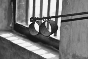 Photo of shackles in front of a barred window