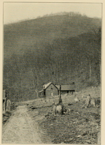 Black & white photo of road running past a house below the knob
