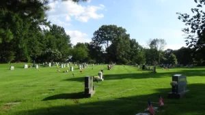 Photo looking up a cemetery hill, from the end of a diagonal line of tombstones
