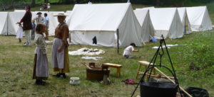 Photo of a woman and child acting as army camp followers in front of a line of tents