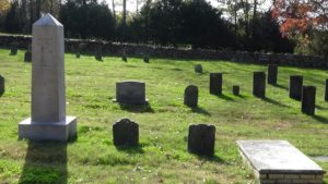 Photo of an obelisk on the left, two small tombstones, and a table marker on the right