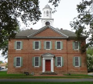 Photo of a two-story brick building, five windows wide, with a white cupola on top