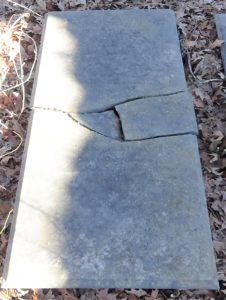 Photo of a flat, grave-length marker broken in the middle