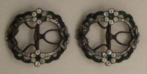 Two buckles side by side, open metal circles with small rhinestones lining the circles and a flower of them on each side, the middle one blue