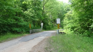 Photo of a short bridge with guardrails on a gravel road