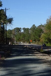 View of a two-lane road going downslope with trees in the background